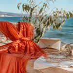 Robe terracotta cérémonie au bord de l’eau, sandales nude et bijoux dorés