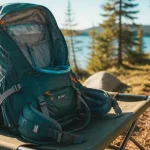 Sac de randonnée 20–30 L ouvert près d’un lac, sangles et ceinture ventrale